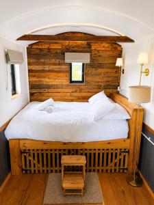 a bedroom with a large bed with a wooden wall at Wiltshire Weavers Hut in Chippenham +10 photos