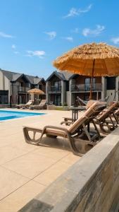 two lounge chairs and an umbrella next to a pool at Apartamenty Marinera in Łeba