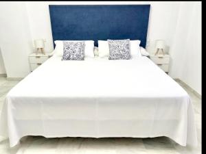 a white bed with two pillows on top of it at MI CAPRICHO BEACHFRONT 410 - Apartment with terrace and private garden by the sea in Mijas Costa +55 photos