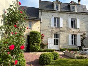 an old stone house with red roses in the yard at Maison D'hôtes Saint-Gildas in Beaufort-en-Vallée
