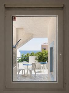 a view of a table and chairs through a window at Blue Dolphin Aegina in Vaia
