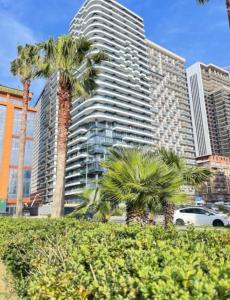 a tall building with palm trees in front of it at Mar y Sol in Batumi