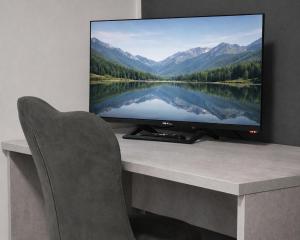 Ein Fernseher steht auf einem Schreibtisch mit einem Stuhl. in der Unterkunft Hotel Genesis in Vignola