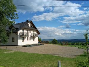 a white house with a balcony on a gravel driveway at Noclegi Widokowa Przystań in Krajno Pierwsze