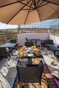 a patio with tables and chairs under an umbrella at Riad Mozaik Fes in Fez