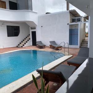 a swimming pool with two chairs and a house at Hospedaje Zerimar Hab 7 in Puerto Baquerizo Moreno