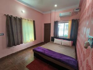 a bedroom with a bed in a room with pink walls at Bhakti Suite in Deoghar