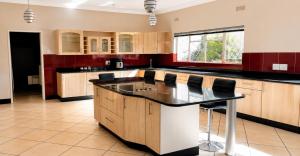 a large kitchen with wooden cabinets and black counter tops at The Vine House in Harare