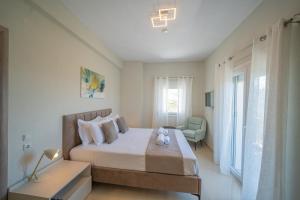 a white bedroom with a bed and a chair at Gerania nature Residence 21 in Siátista
