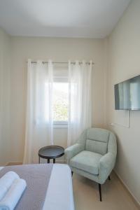 a bedroom with a bed and a chair and a window at Gerania nature Residence 21 in Siátista +24 photos