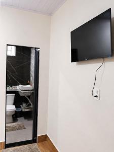 a bathroom with a toilet and a television on a wall at Chácara Orvalho da Chapada in Cavalcante +11 photos