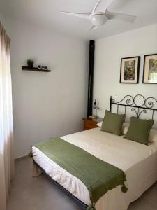 a bedroom with a bed with green pillows and a ceiling fan at Casa Chica in Cazorla