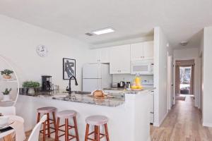 a kitchen with white cabinets and bar stools at The YinYang - King Bed , Workspace , Full Kitchen in Gainesville