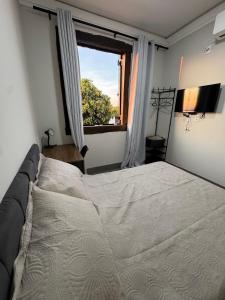 a bedroom with a large bed and a window at Pousada Carro de Boi in Lavras