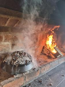 a fire in a brick oven with a pan of food at Vikendica BeeLux in Banja Luka