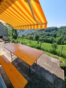a wooden table and bench under an orange umbrella at Vikendica BeeLux in Banja Luka