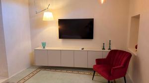 a living room with a tv and a red chair at B&B Casa di Leo in Brindisi