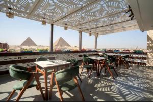 a patio with tables and chairs and the pyramids at Pyra King Royal Pyramids Hotel in Cairo
