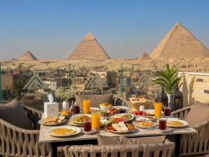 a table full of food with the pyramids in the background at Lava pyramids hotel in Cairo