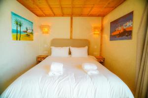 a bedroom with a white bed with two towels on it at Villa Aloe Vera Privée in Essaouira +17 photos