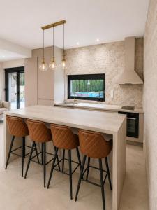 a kitchen with a large island with bar stools at LUXIA PRIVATE ESTATE Sauna & Pool x Jacuzzi with Fireplace outdoor lounge in Bihać