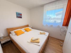 a bedroom with a bed with yellow pillows and a window at Apartments TORO Pag in Pag