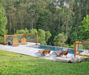 a pool with three chairs and avisorvisor at T3 Quinta da Melroa - Mountain Villa - Caramulo in Viseu