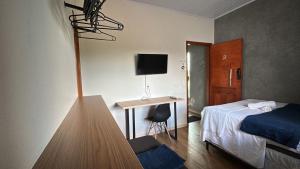 a hotel room with a bed and a desk with a television at Flat hotel Victoram in Rio Branco