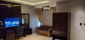 a living room with a couch and a flat screen tv at Charles Stainless Hotels in Abakaliki