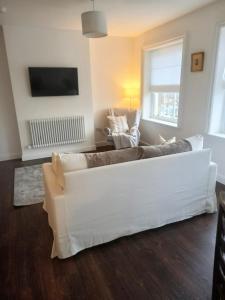 a living room with a white couch and two chairs at Clubhouse 3 in Bedale