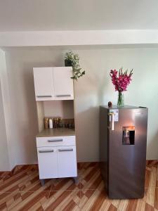 a kitchen with a refrigerator and a shelf with flowers at Wiracocha Apartments #1 in Cusco