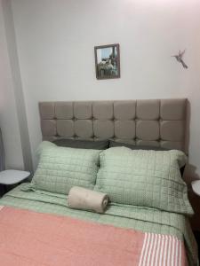 a bed with green pillows and a picture on the wall at Wiracocha Apartments #1 in Cusco