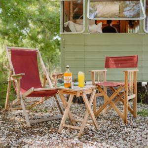 two chairs and a table with a bottle of orange juice at Olívia, Caravana Vintage, Castelo de Vide in Castelo de Vide