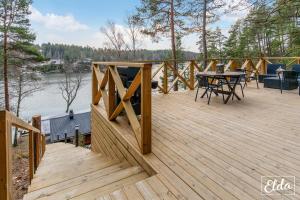 a wooden deck with a table on the side of a lake at Paraisten Helmi in Lönäs +26 photos