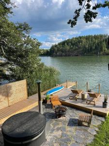 a dock with chairs and a swimming pool next to a lake at Paraisten Helmi in Lönäs