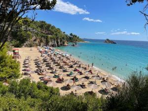 a beach with many umbrellas and people in the water at Makis & Lena's Home in Svoronata