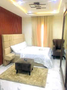 a bedroom with a bed and a chair and a ottoman at Vintage Apartment in Araromi