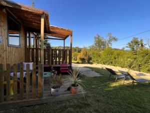 a cabin with a porch and a table and chairs at O'BARA Lodge - Tiny House - Jardin et climatisation in Druillat