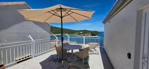 a patio with a table and an umbrella on a balcony at Apartmani Luan in Vis