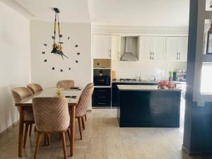 a kitchen with a table and chairs and a clock on the wall at Lengliz in Kelibia
