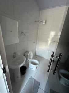 a white bathroom with a toilet and a sink at Hotel São Miguel in Posse