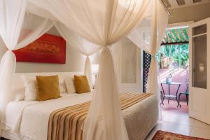 a bedroom with a white bed with a canopy at Pedra da Laguna Boutique Hotel SPA in Búzios