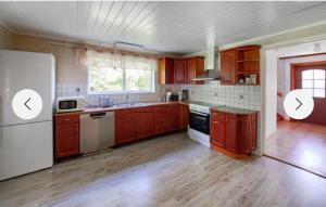 a kitchen with wooden cabinets and a white refrigerator at Grå villa in Vislanda