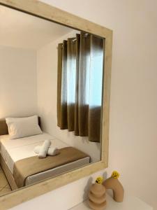 a mirror on a wall with a bed in a room at Sempre, Florida Suites, Kythira in Agia Pelagia