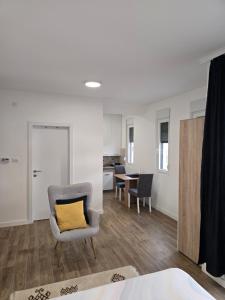 a living room with a chair and a yellow pillow at Kmb Apartment in Kragujevac