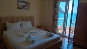 a bedroom with a bed with a view of the ocean at Magic Ionian Apartments & Rooms in Himare