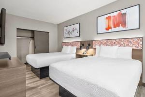 a hotel room with two beds and a tv at Hawthorn Extended Stay by Wyndham DFW Airport North in Irving