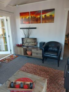 a living room with a black leather chair and a table at The Cosy Nook in Waimate
