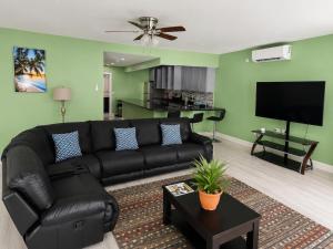 a living room with a black couch and a flat screen tv at Torraille Waterfall Villas Main Suites in Soufrière