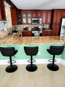 a kitchen with three bar stools in front of a counter at Torraille Waterfall Villas Main Suites in Soufrière